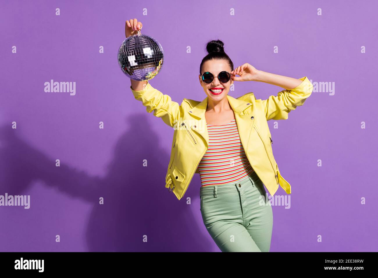 Photo of cool positive girl hold glitter discotheque ball touch specs isolated over violet color background Stock Photo