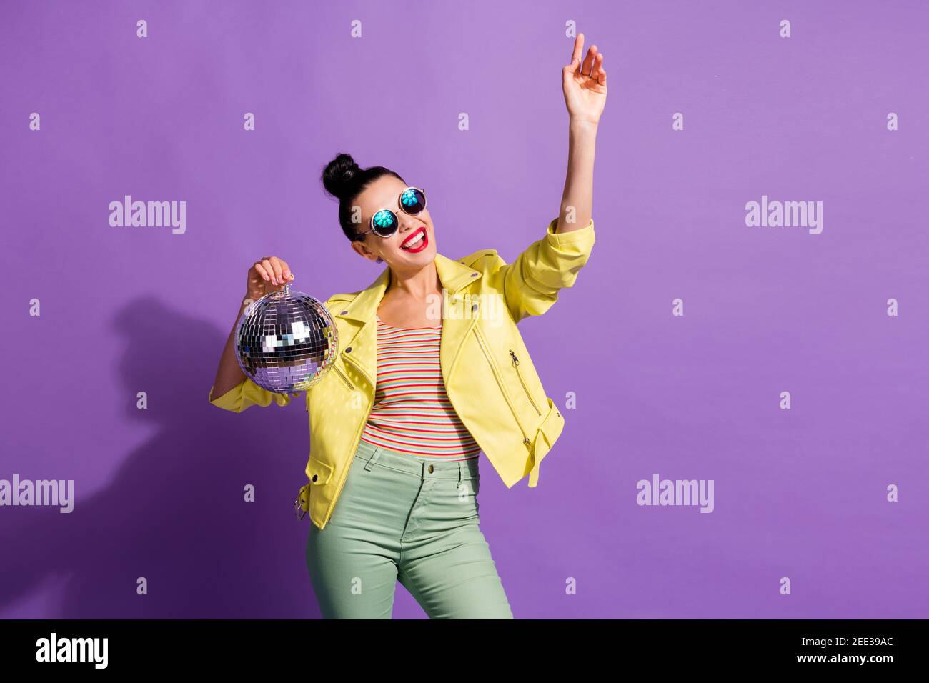 Photo of cool youth girl hold glitter ball raise hand look empty space isolated over violet color background Stock Photo