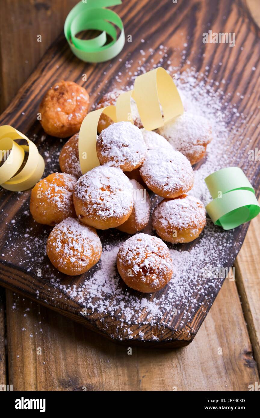Baked castagnole with powdered sugar and confetti. Street food, round