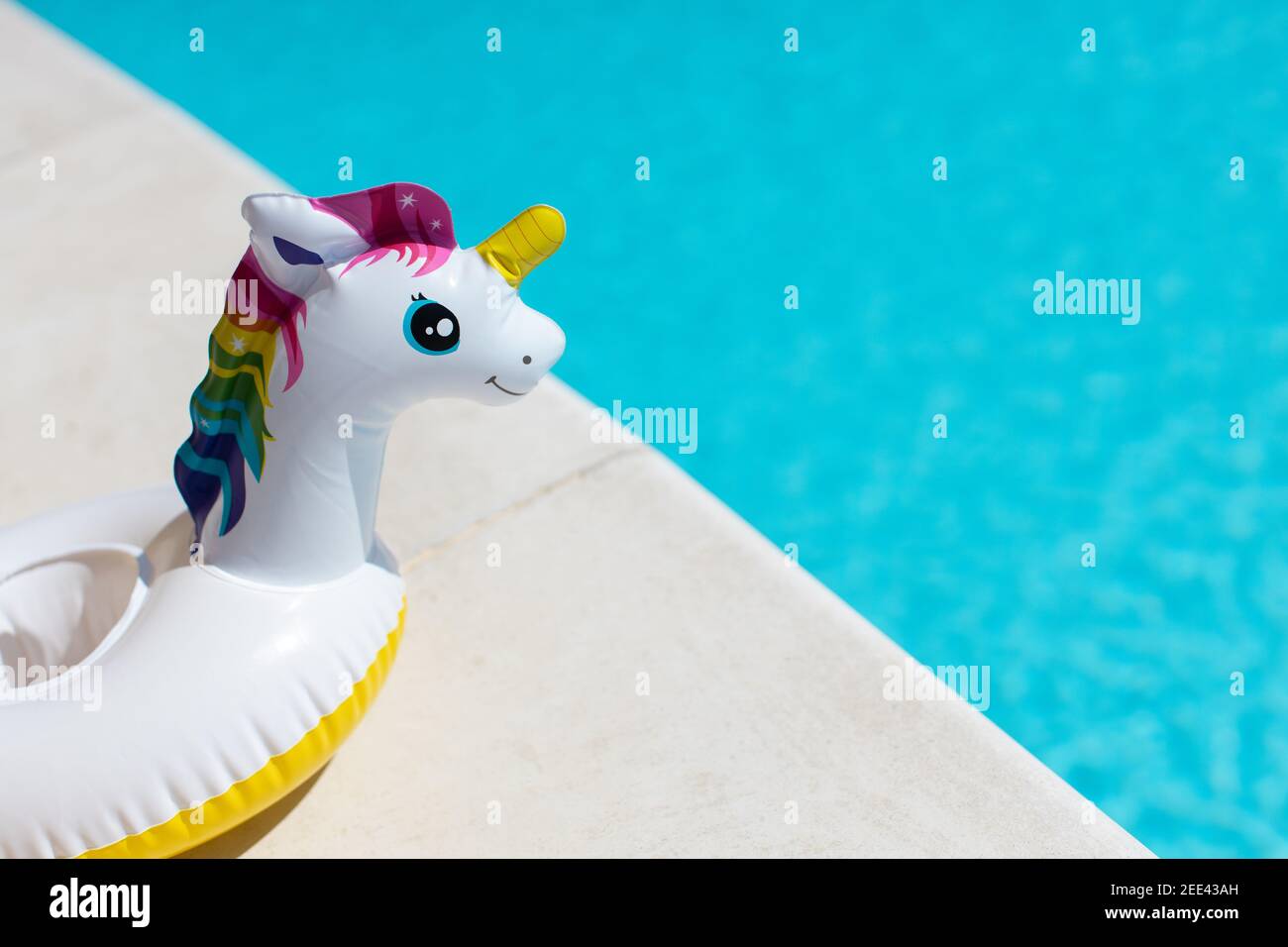 Inflatable pink mini rainbow unicorn, cocktail stand near swimming pool on bright sunny day, copy space. Concept summer vacation, entertainment, water Stock Photo