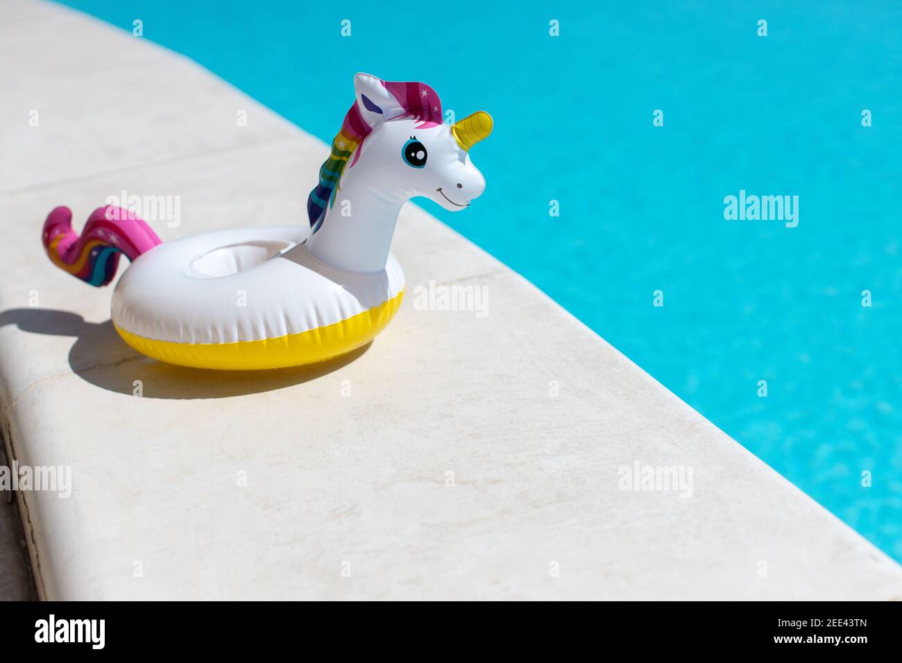 Inflatable pink mini rainbow unicorn, cocktail stand near swimming pool on bright sunny day, copy space. Concept summer vacation, entertainment, water Stock Photo