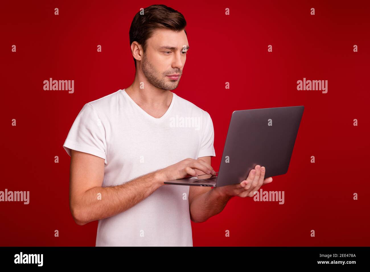 Photo portrait of young programmer working with laptop concentrated focused isolated vibrant red color background Stock Photo