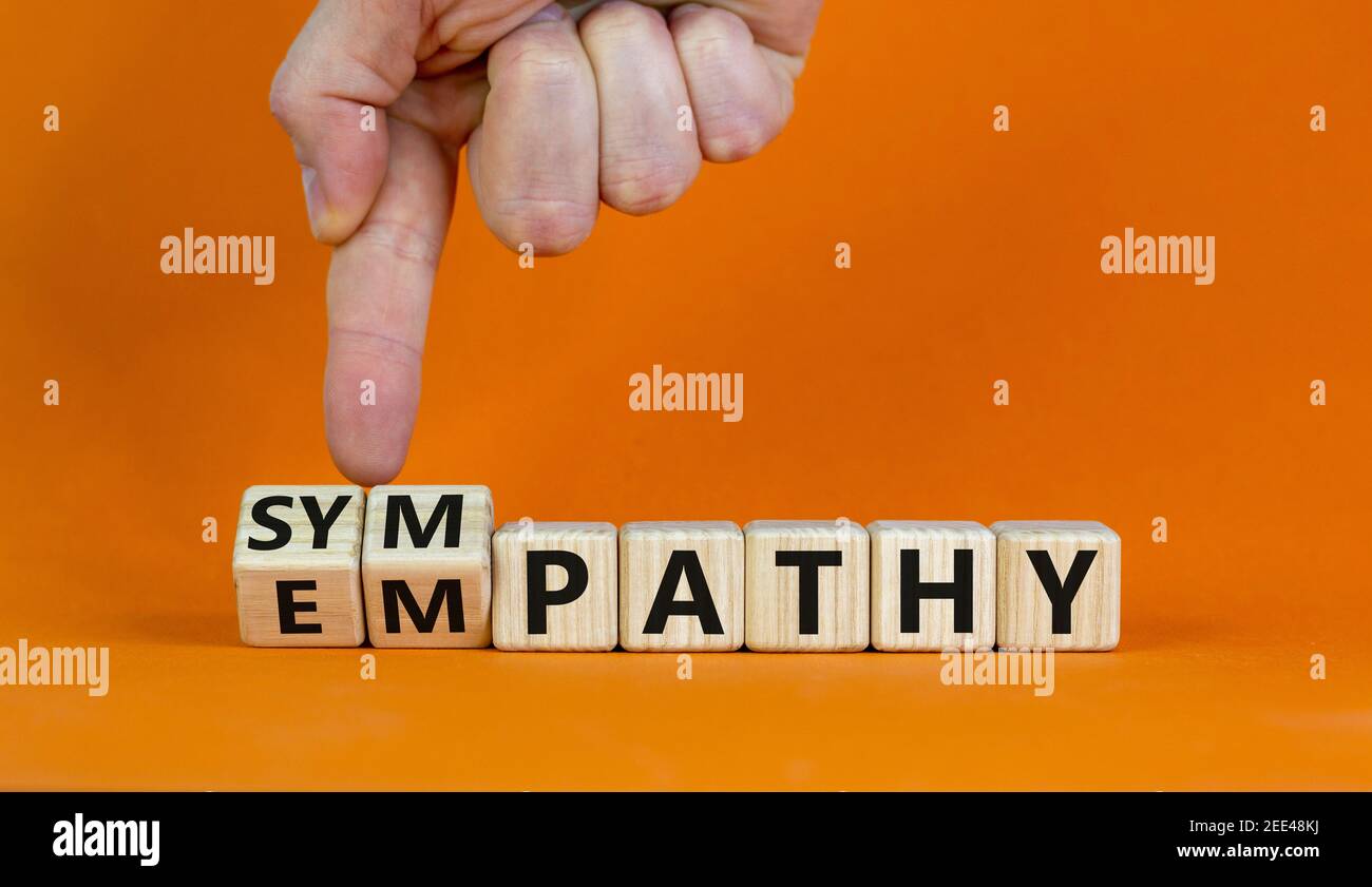 From empathy to sympathy. Businessman turns cubes and changes the word 'empathy' to 'sympathy'. Beautiful orange background. Copy space. Psychological Stock Photo