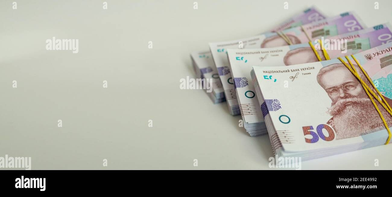 Bundles of 50 hryvnia banknotes are stacked on a light gray background ...