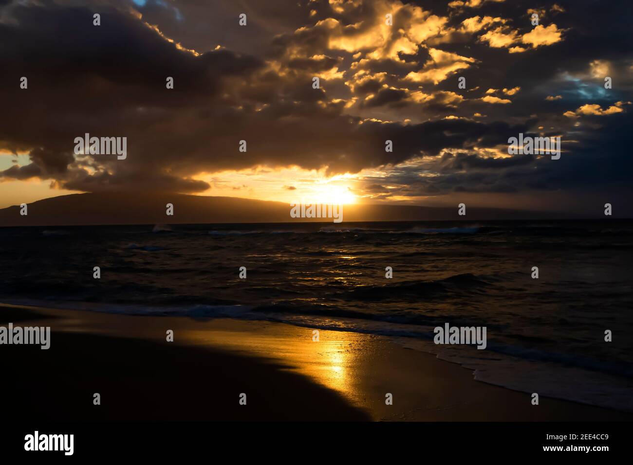 Sunset reflected in wet sand on beach in twilight seascape in Hawaii. Stock Photo