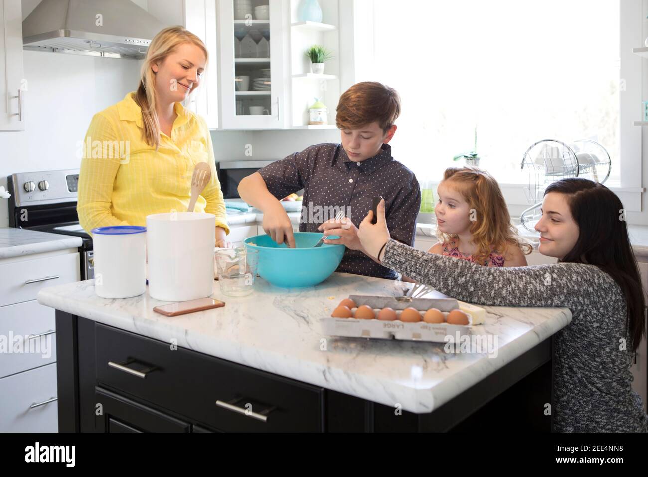 A family baking together as the daughter takes a selfie. Stock Photo