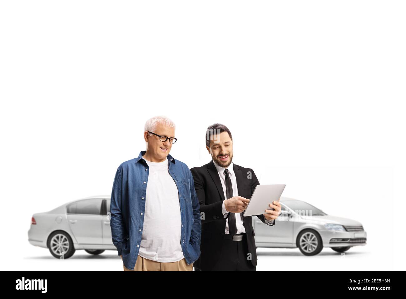 Car salesman and a mature customer looking at a tablet in a car showroom isolated on white background Stock Photo