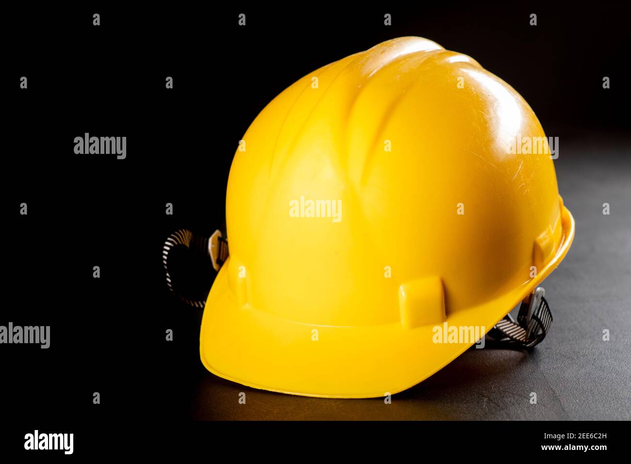 Yellow work helmet on a dark table. Protective accessories for construction workers. Dark background. Stock Photo
