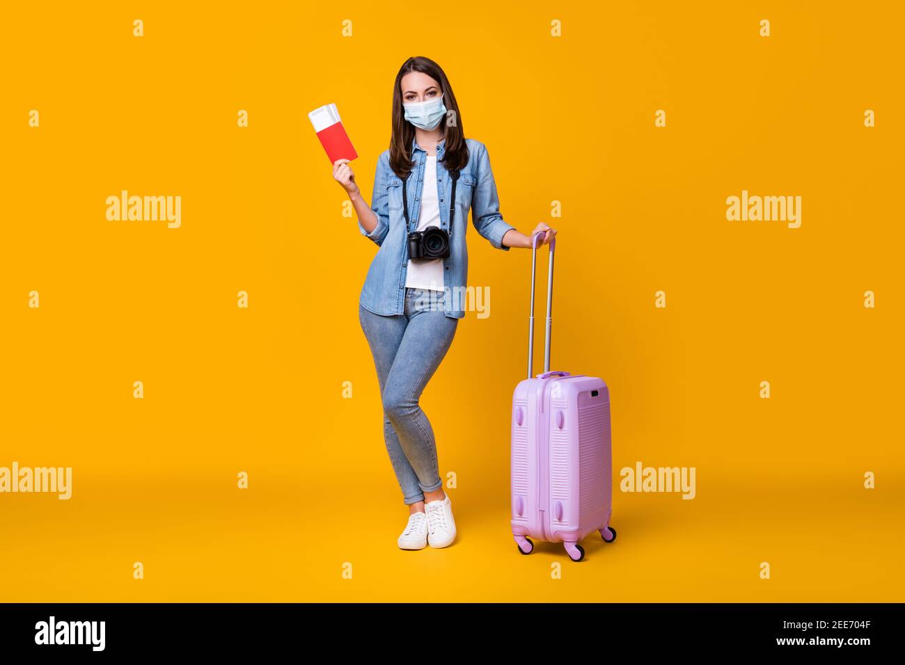 Full size photo of young lady journalist rolling bag photographer travel abroad airport quarantine registration tickets wear facial mask casual Stock Photo