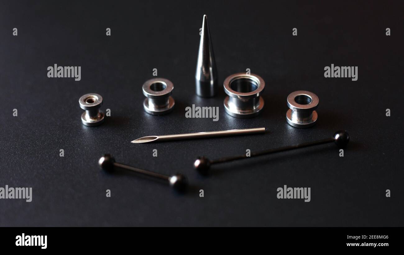 Set for piercing on a dark background, ear tunnels, tunnels and earrings for the ears and tongue