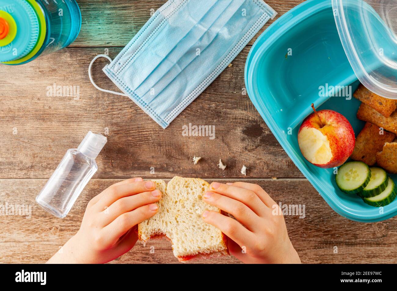 Flat lay image with eating lunch at school concept during the phased reopening after COVID-19 pandemic closures. Snack in containers as well as water Stock Photo