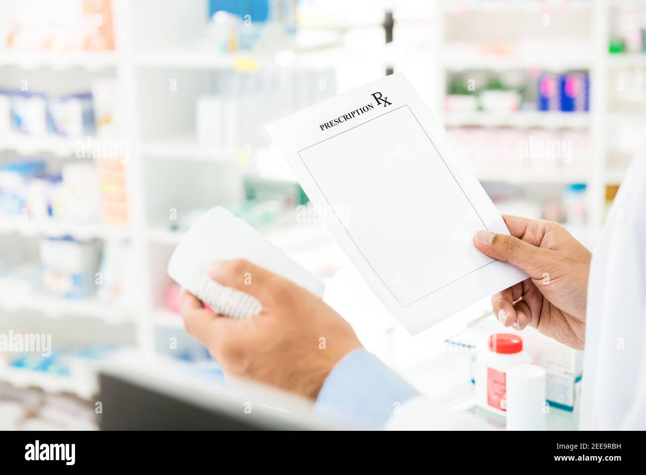 Pharmacist reading label on medicine bottle checking with prescription in pharmacy Stock Photo