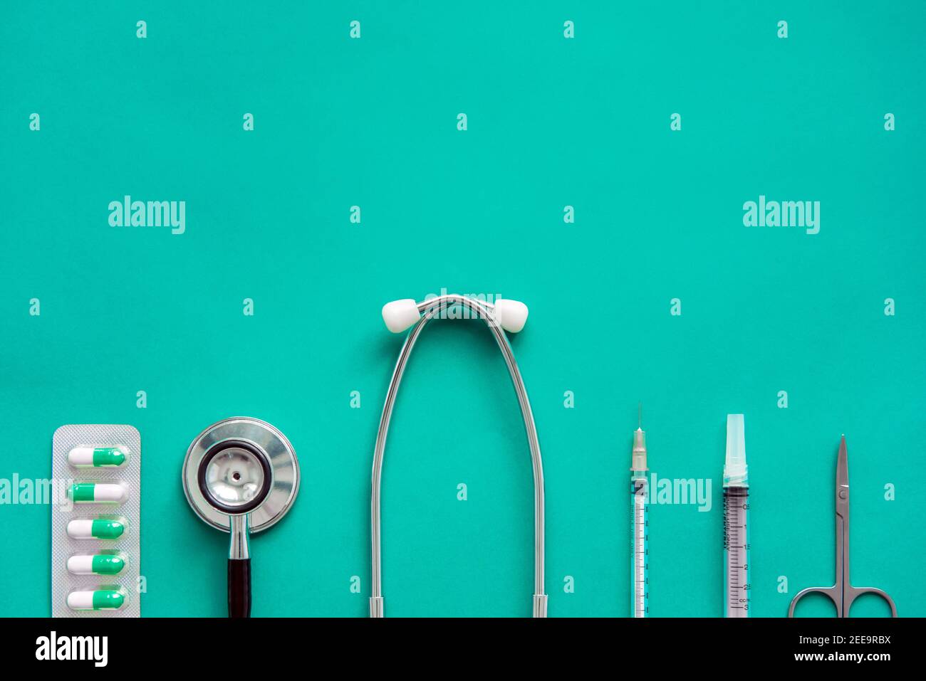 Medical equipments including stethoscope, scissors, syringes and capsules on green background, top view Stock Photo