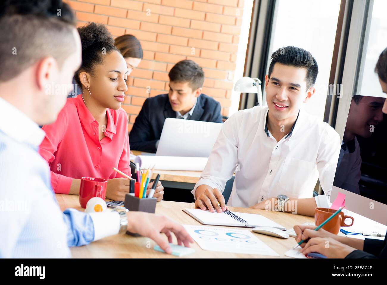 Young casual multiethnic business team discussing project in the meeting Stock Photo