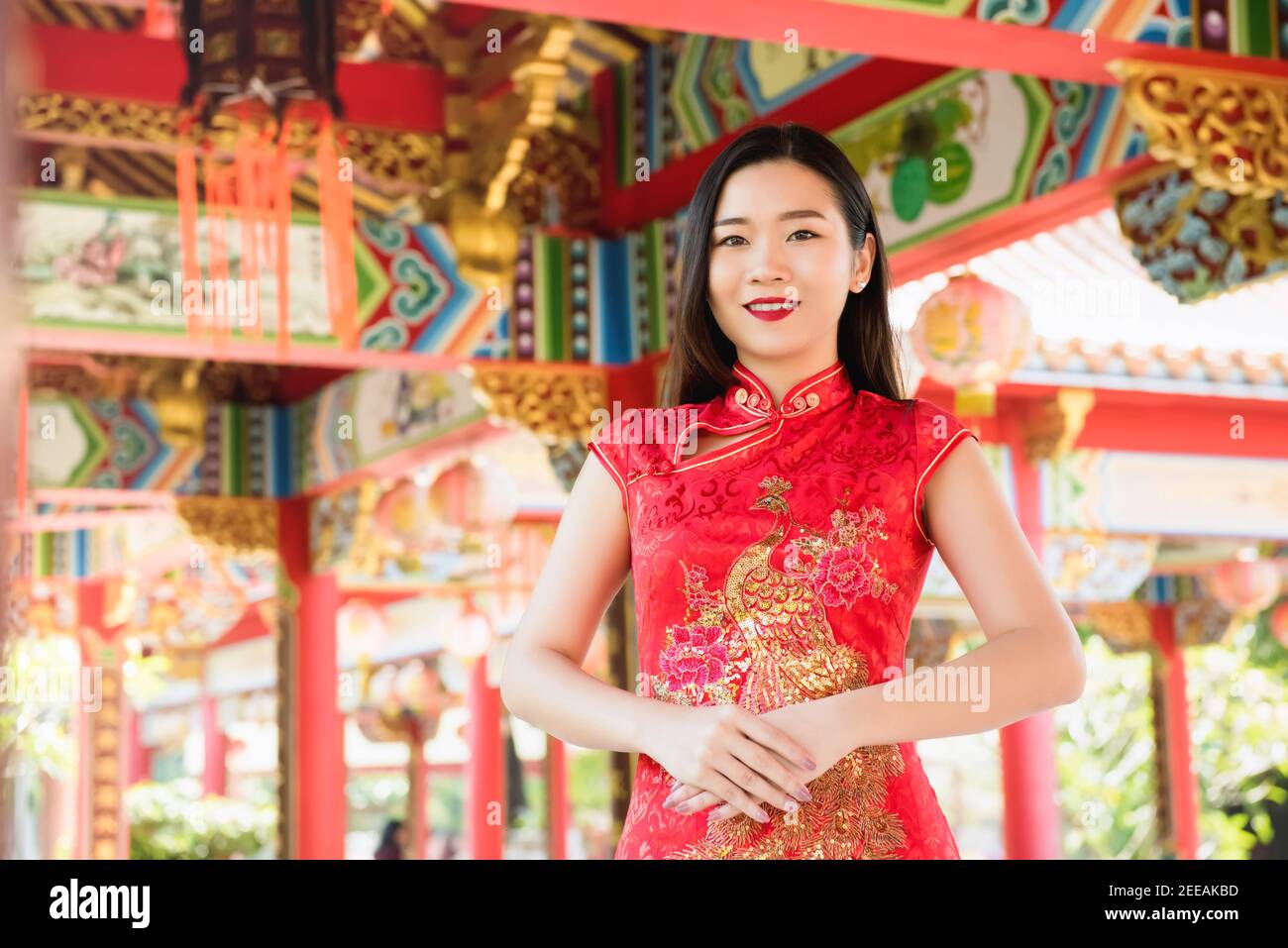 Smiling beautiful Asian woman in traditional red cheongsam qipao dress  at Chinese temple Stock Photo