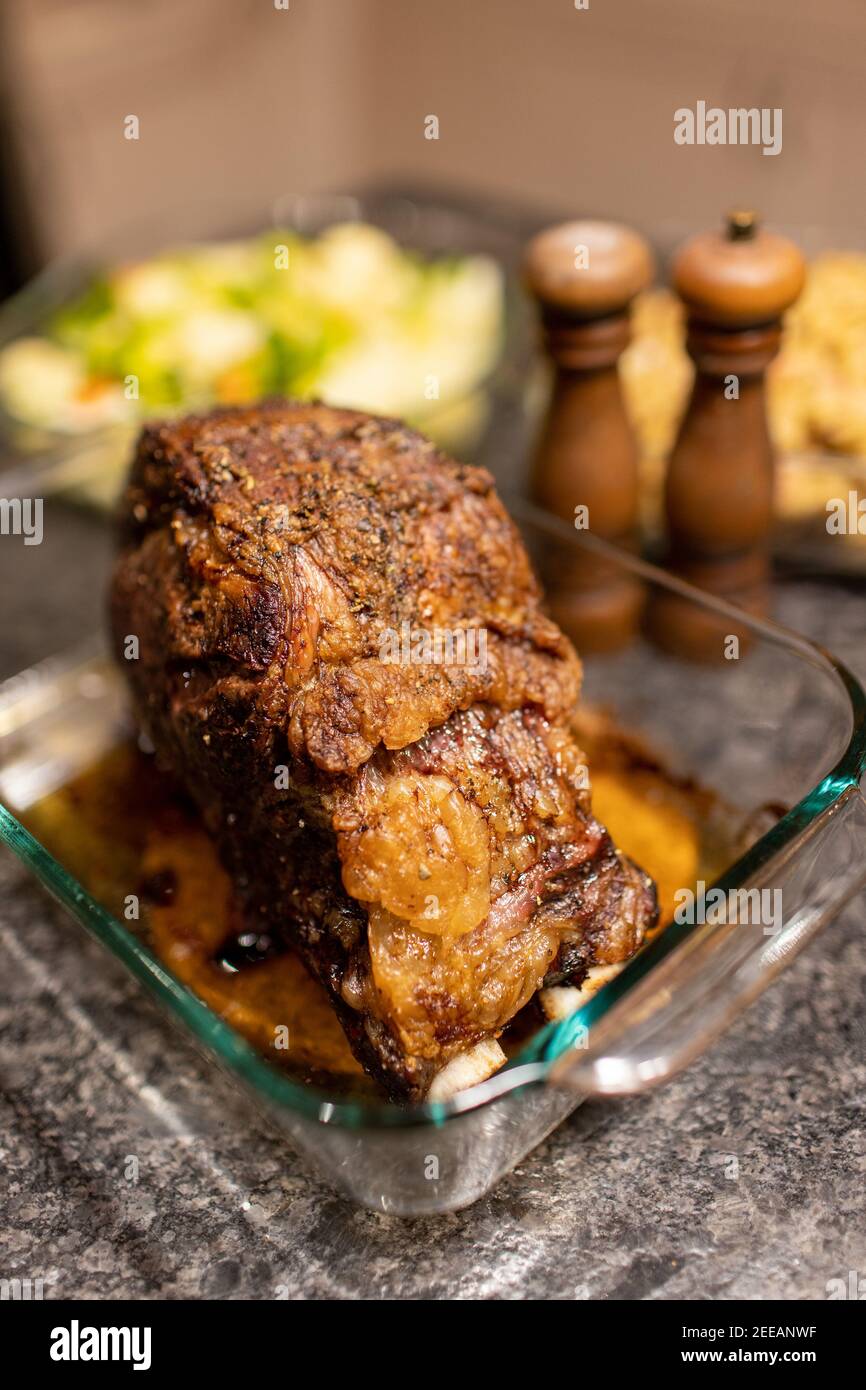 Prime rib roast beef dinner with salt and pepper shakers and dishes in the background Stock Photo
