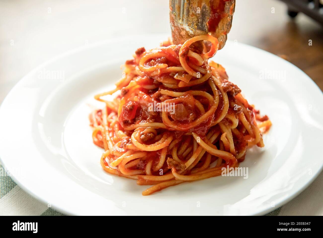 Traditional Italian spaghetti bolognese pasta being plated at the table Stock Photo