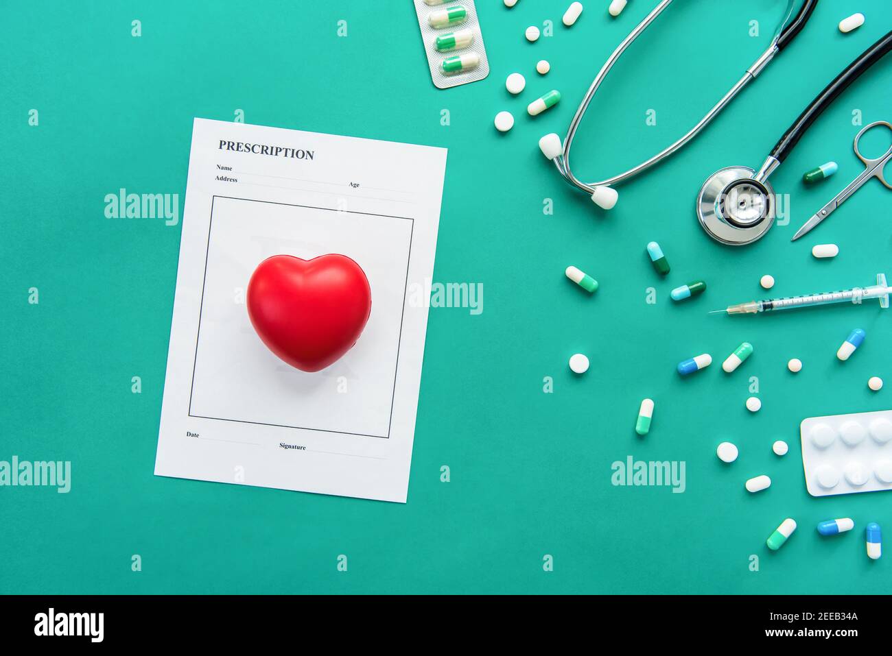 Drugs and medical instruments including stethoscope, syringe, scissors and prescription with red heart shape ball on green background Stock Photo