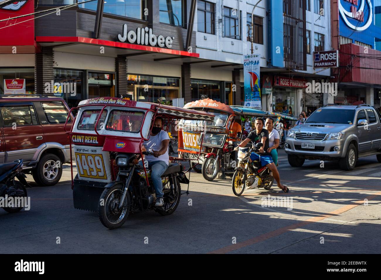 Dumaguete, the Philippines - 10 Mar 2019: Motorbike on asian city street. Filipino tricycle and bike. Jollibee cafe. Street traffic in Asia. Modern ci Stock Photo