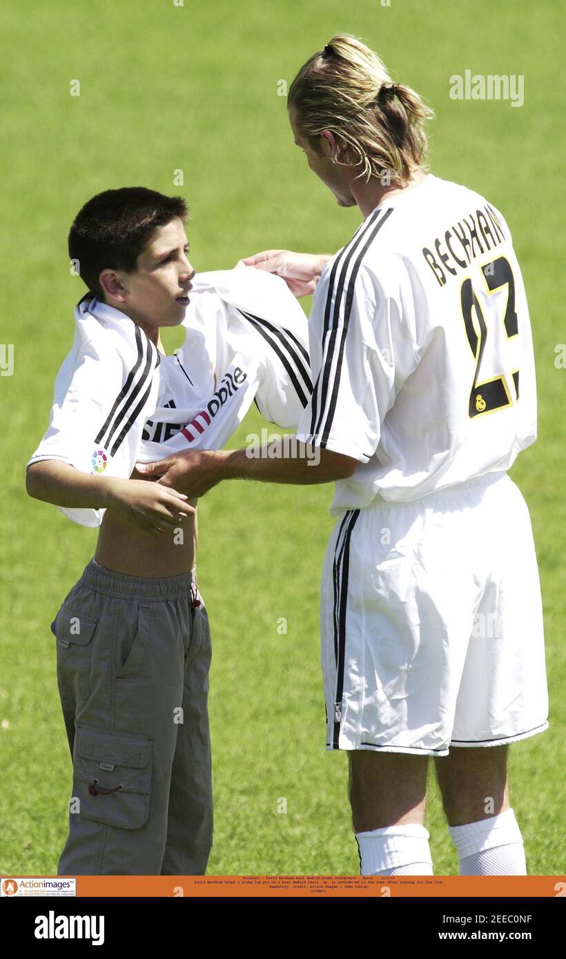 Football - David Beckham Real Madrid Press Conference - Spain - 2/7/03 David  Beckham helps a young fan put on a Real Madrid Shirt as is introduced to  the fans after signing