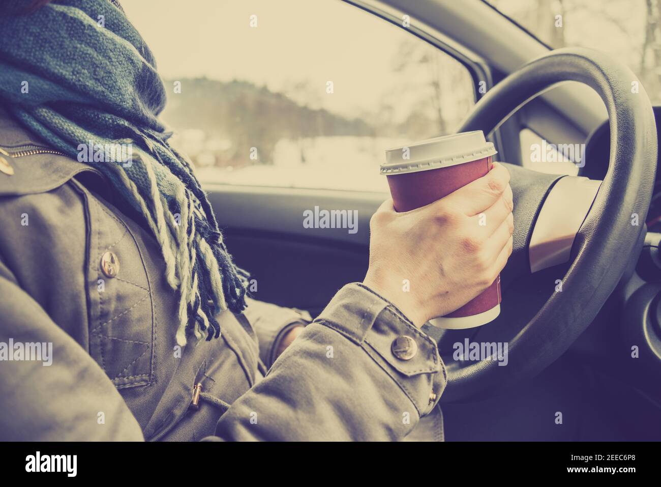 Driver drinking coffee in the car, driving and holding a steering wheel