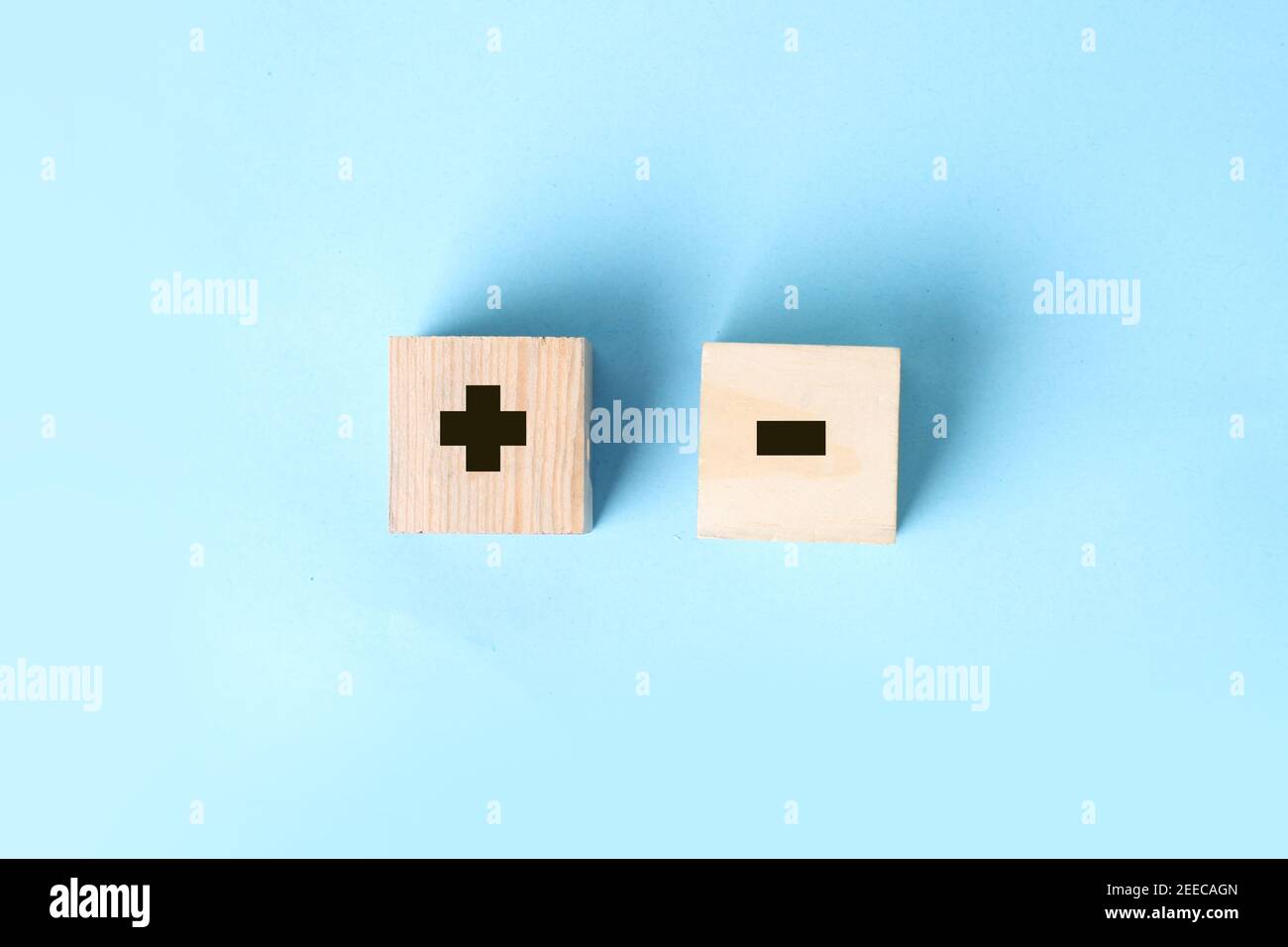 Wooden block in hand on a blue background with plus and minus signs. Decision making business concept Stock Photo
