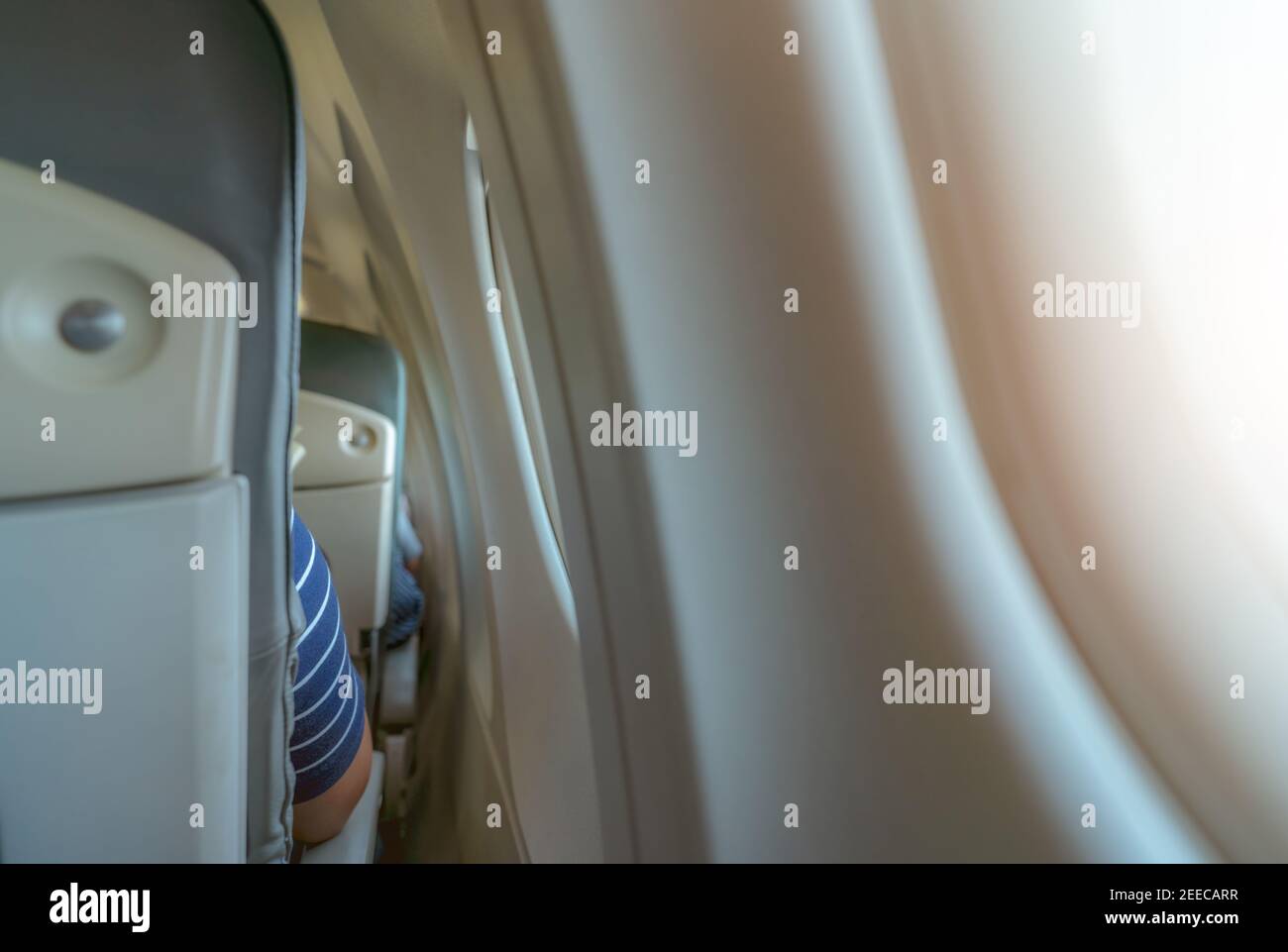 Rearview of airplane seat near plane window. Economy class airplane. Inside of commercial airline. Small space between passenger economy seat. Stock Photo