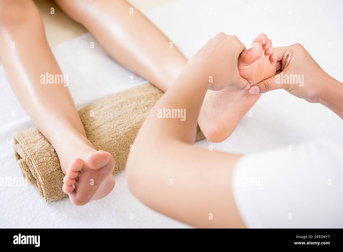 Professional therapist giving relaxing reflexology Thai foot massage treatment to a woman in spa Stock Photo