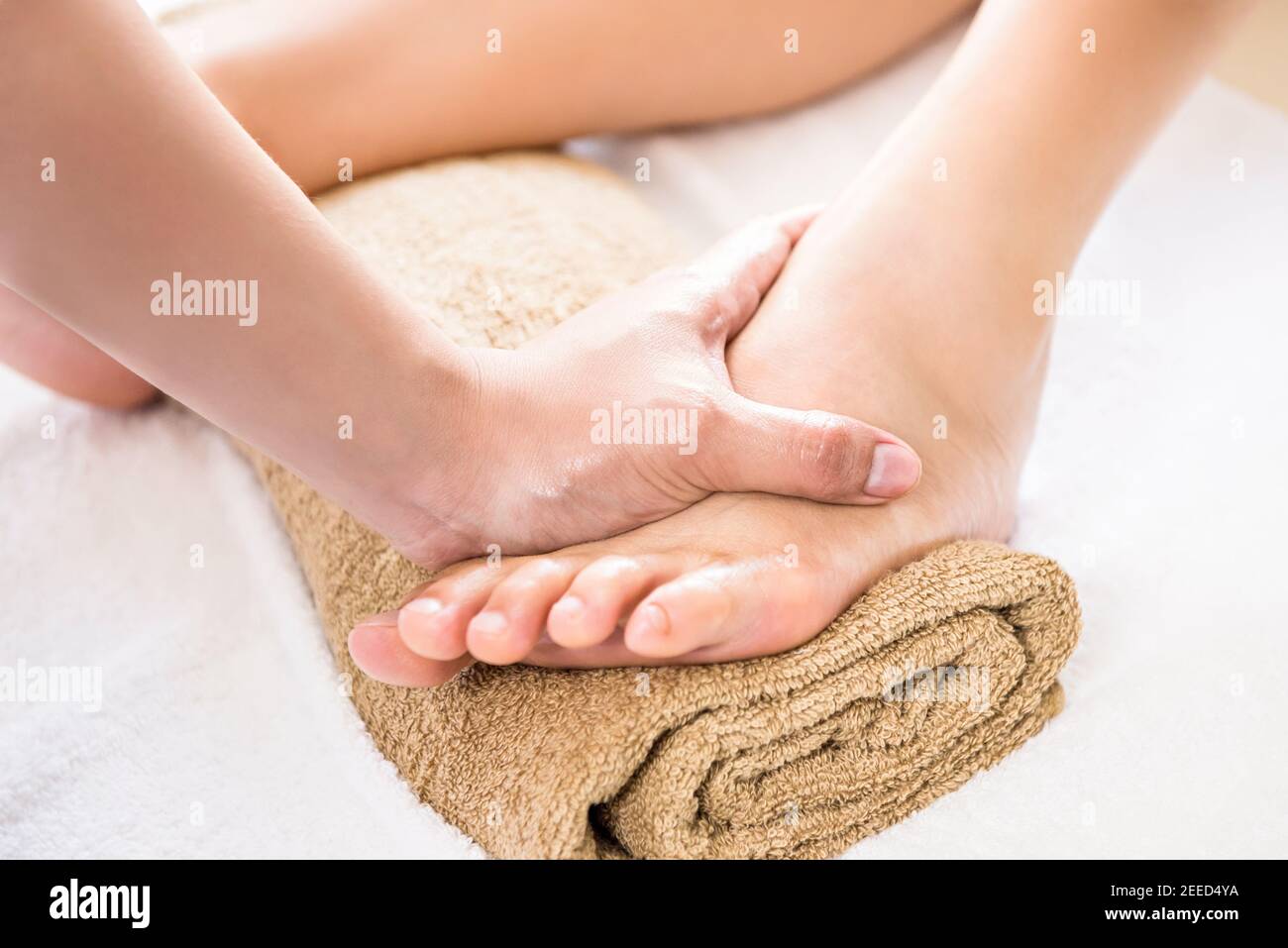 Professional therapist giving relaxing reflexology foot massage treatment to a woman in spa Stock Photo