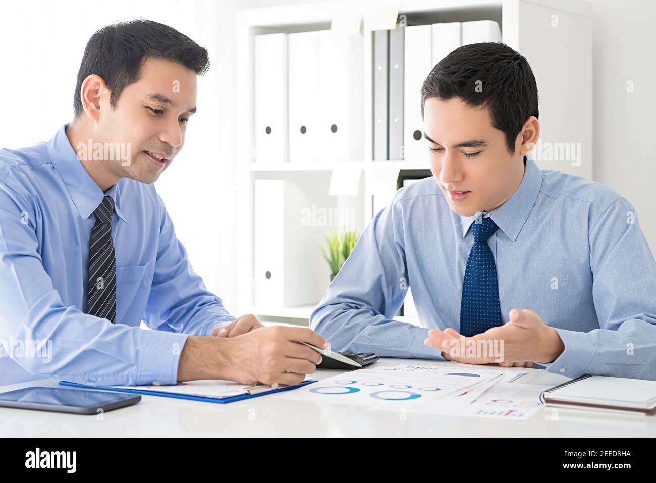 Asian businessmen analyzing and discussing work presentation documents at meeting table in the office Stock Photo
