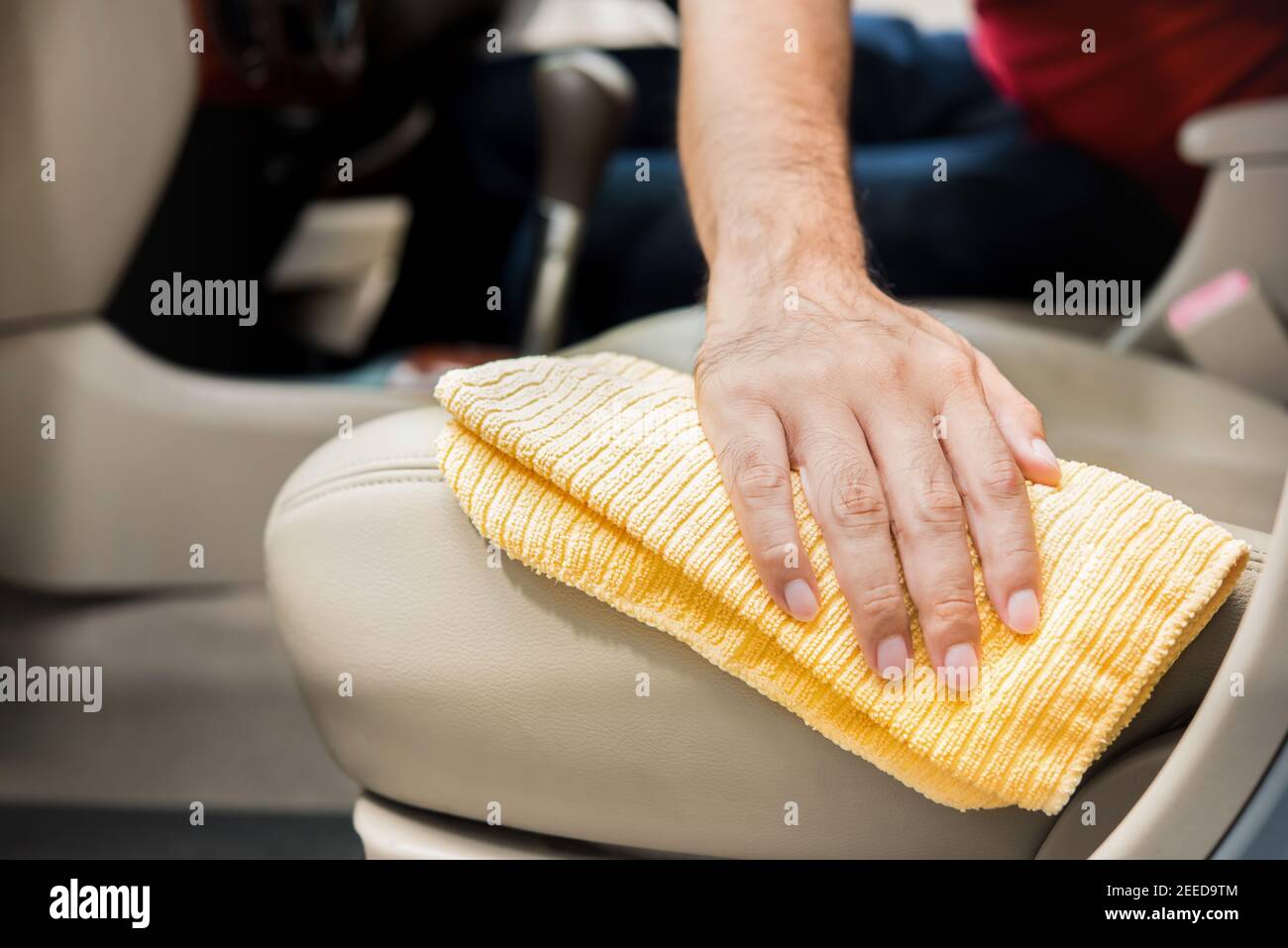 A man cleanining beige leather car seat with microfiber cloth - auto detailing and valeting concept Stock Photo