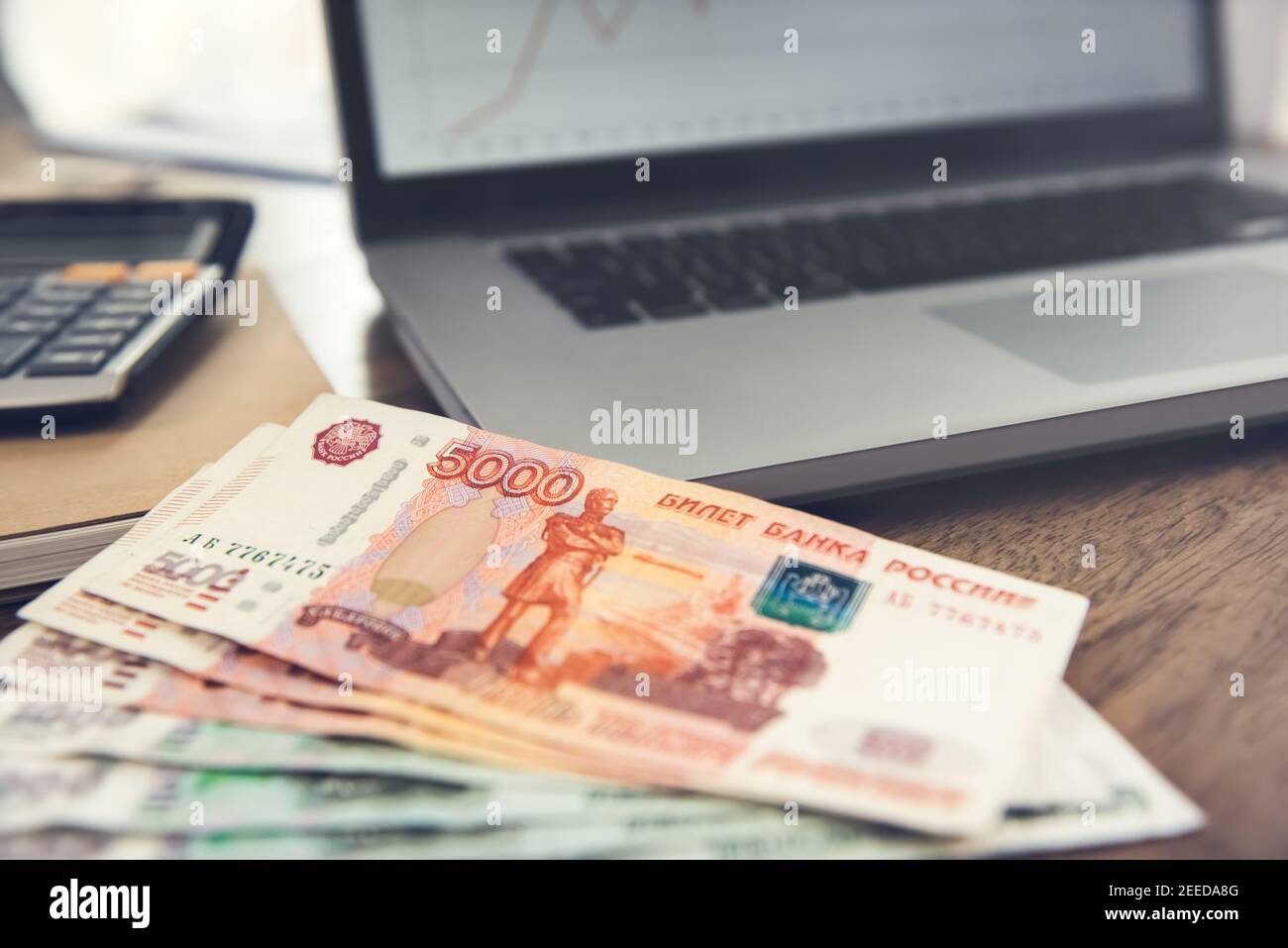 Russian Ruble money banknotes on wooden desk with a laptop computer and a calculator - online financial planning and investment concepts Stock Photo