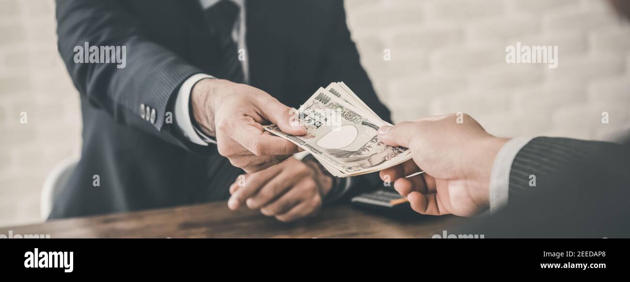 Businessman accepting Japanese Yen money as a bribe, loan or payment in the office - panoramic banner Stock Photo