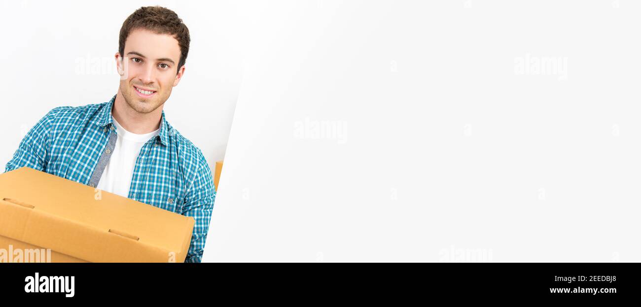 A handsome caucasian man carrying a courier box into new house - horizontal web banner with copy space on the right Stock Photo