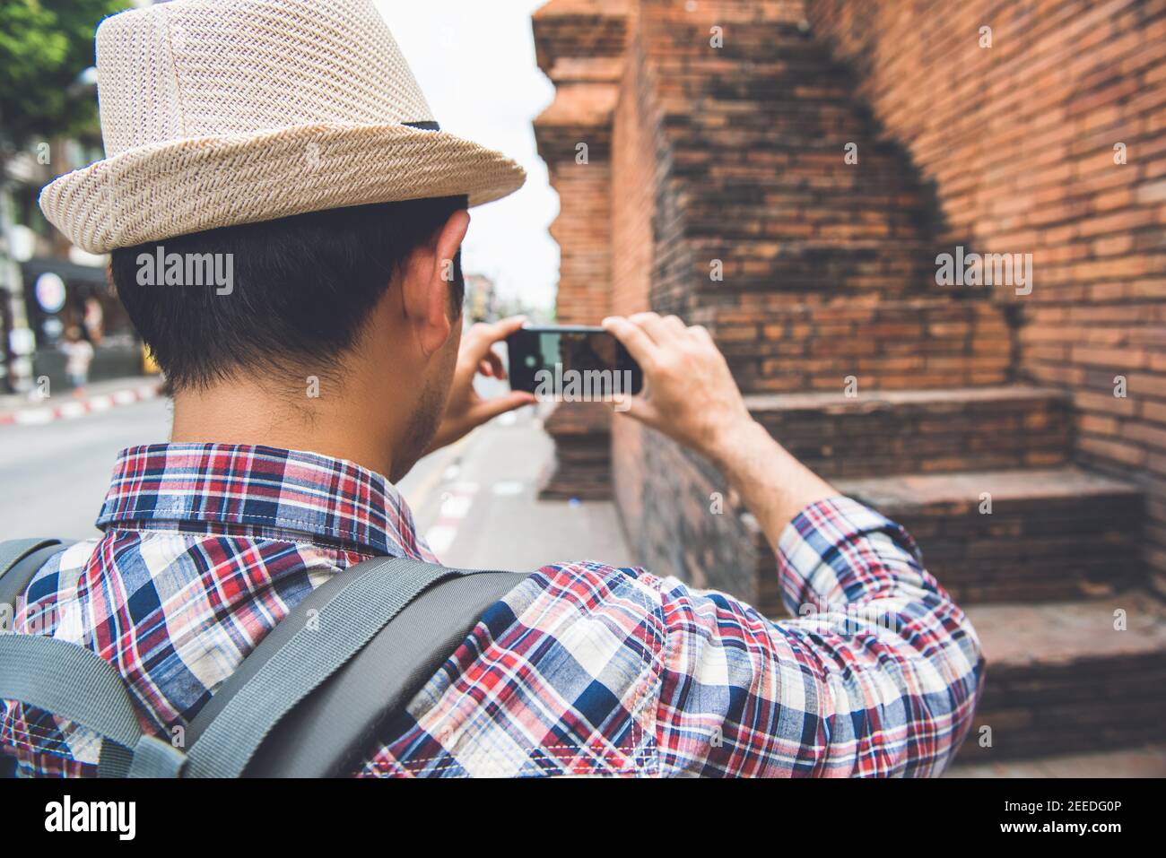 Asian male tourist backpacker taking picture with smartphone at Tha Phae Gate, one of the ancient famous landmark of the city in Chiang Mai Thailand Stock Photo