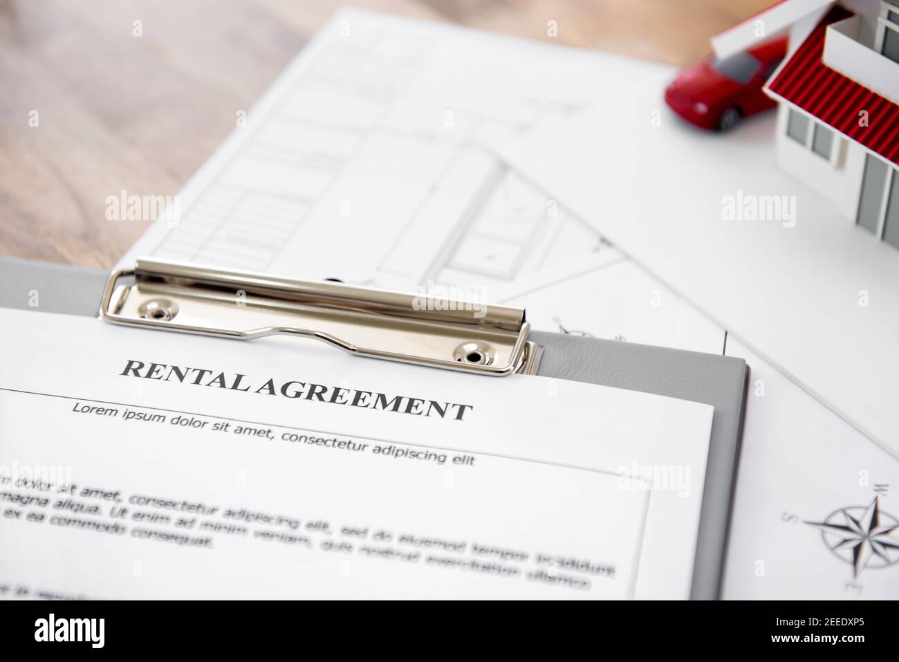 Rental agreement contract paper with blueprints and house model on the table - property and real estate concept Stock Photo
