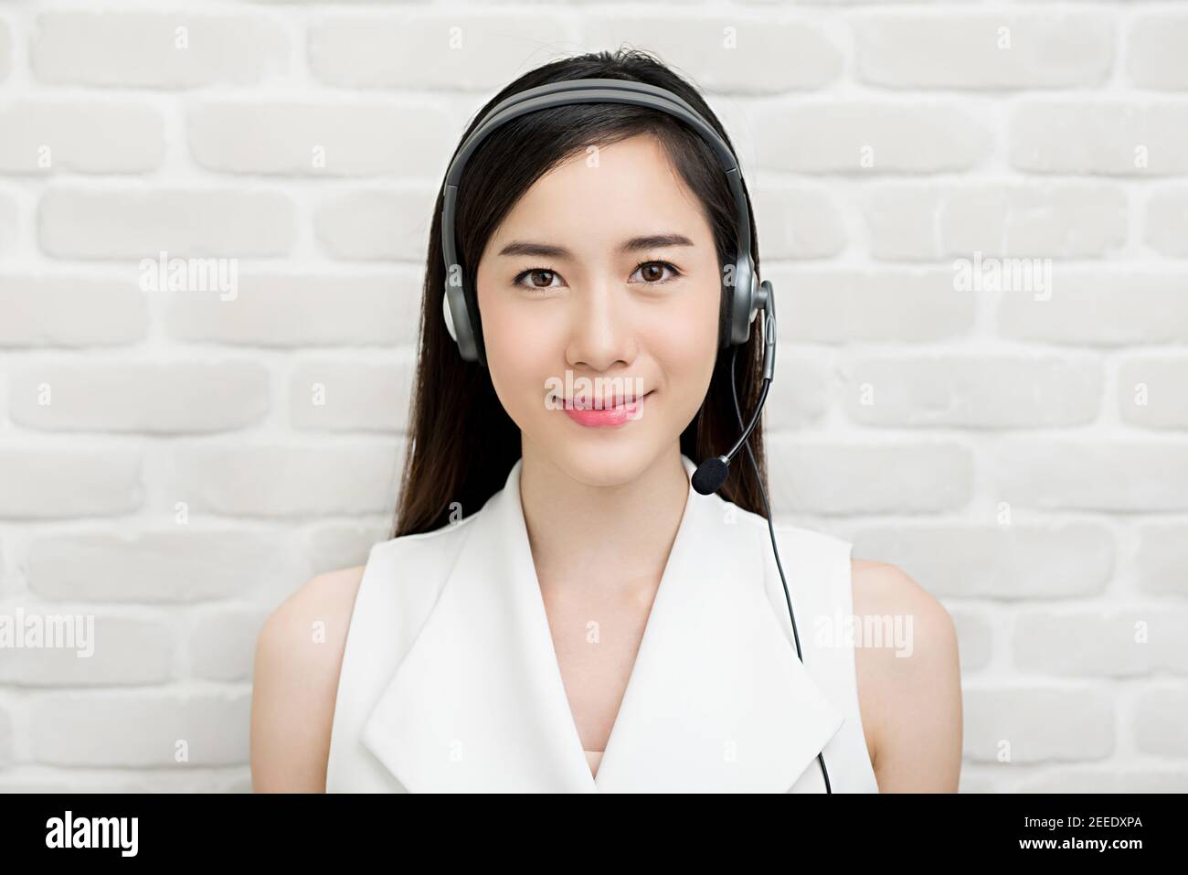 Beautiful Asian businesswoman wearing microphone headset  as a telemarketing customer service agent, call center job concept Stock Photo