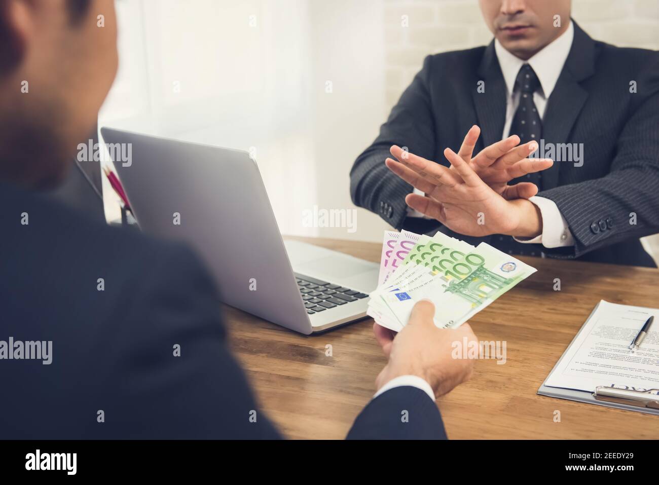 Businessman rejecting money, Euro banknotes, from his partner while making contract agreement - anti bribery concept Stock Photo