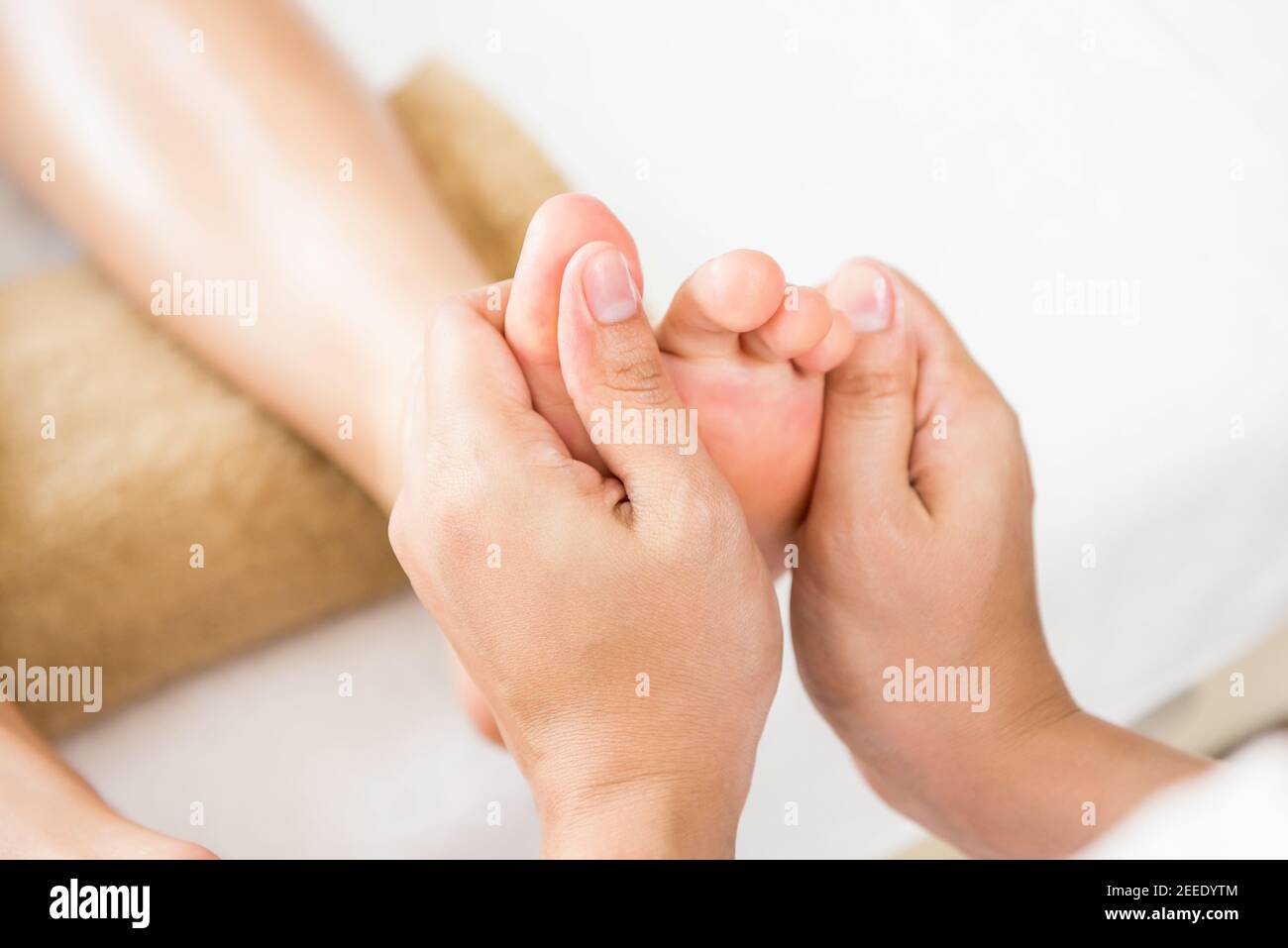 Professional therapist giving relaxing reflexology Thai foot massage to a woman in spa Stock Photo