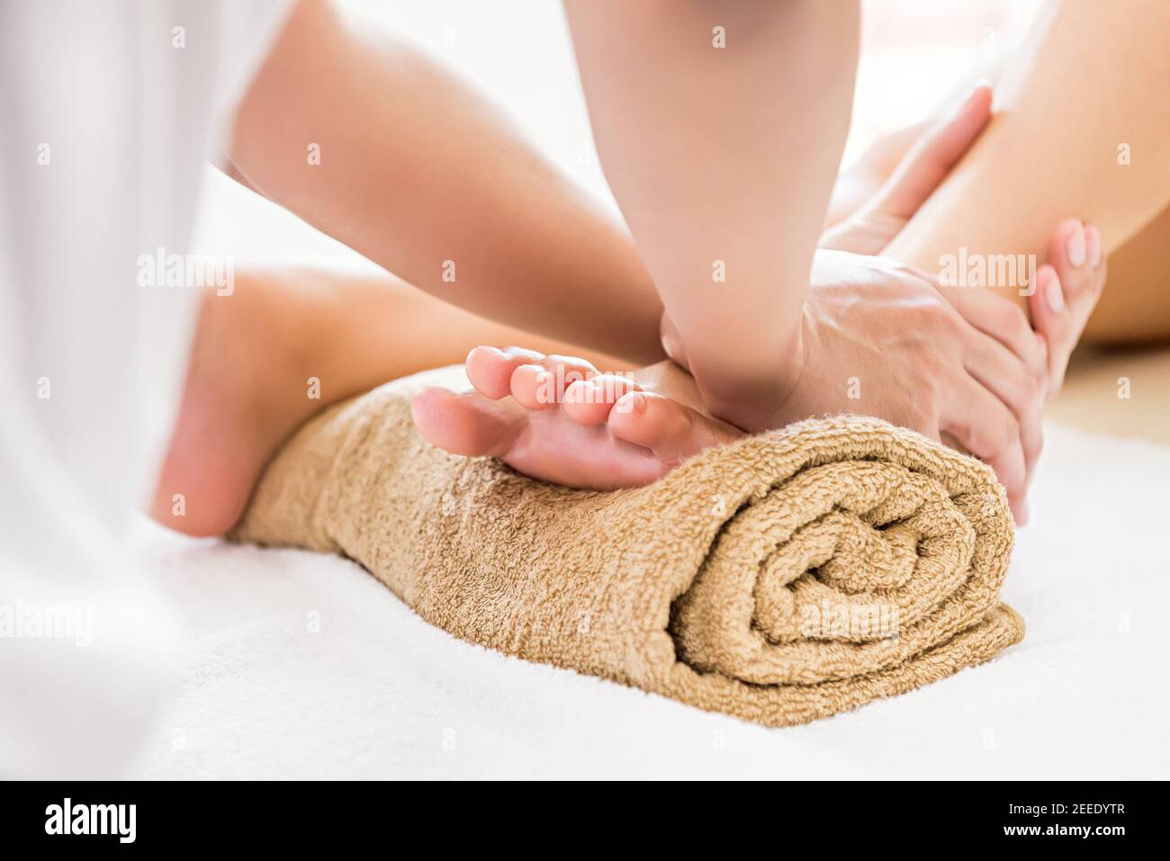 Professional therapist giving relaxing reflexology foot massage to a woman in spa Stock Photo