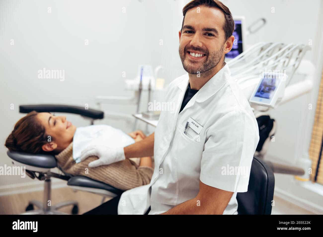 Successful male dentist in his clinic. Dental expert with female patient at dentistry. Stock Photo