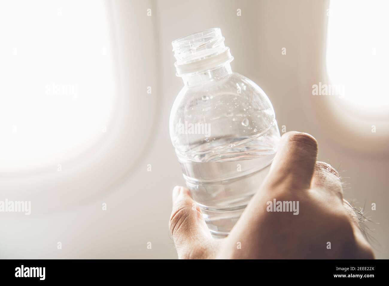 Passenger holding bottle of water about to drink preventing dehydration