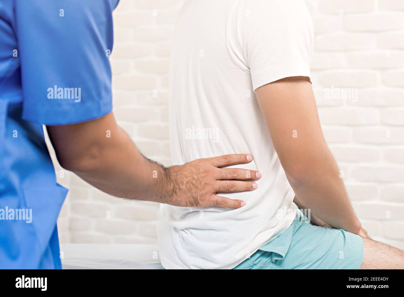 Male doctor therapist treating lower back pain patient in clinic or hospital - physical therapy concept Stock Photo