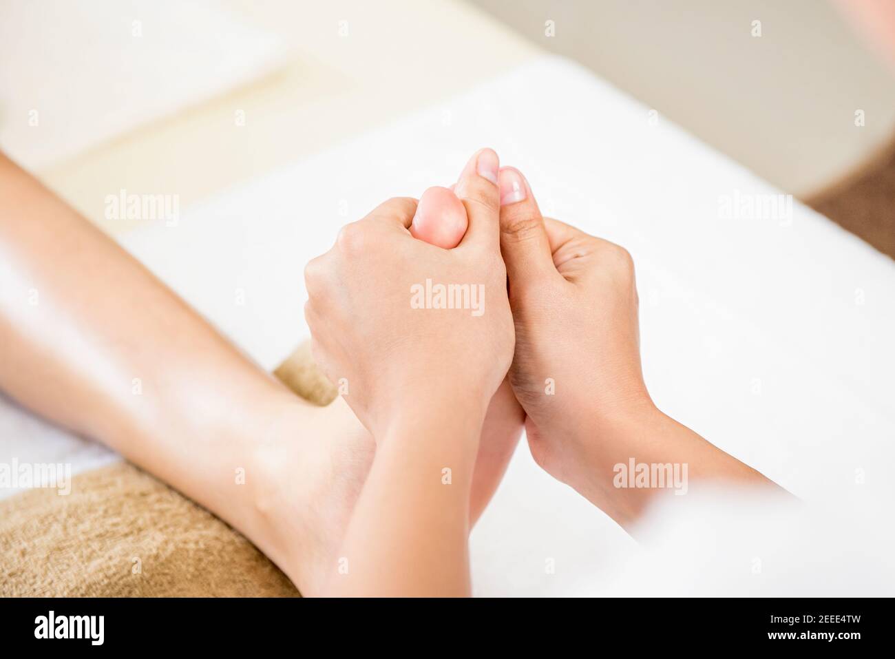 Professional therapist giving relaxing reflexology Thai foot massage to a woman in spa Stock Photo