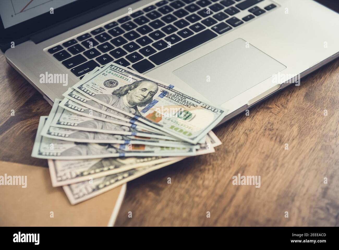 Money, US dollar bills, on laptop computer at working table - investment and financial management concepts Stock Photo