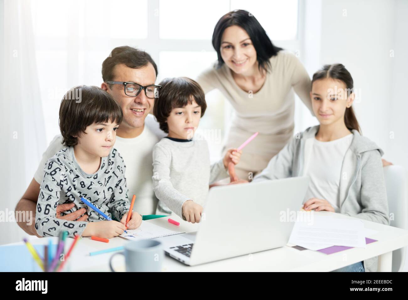 Happy latin family with children spending time together at home. Father watching cartoons together with kids while using laptop. Technology, family concept. Selective focus Stock Photo