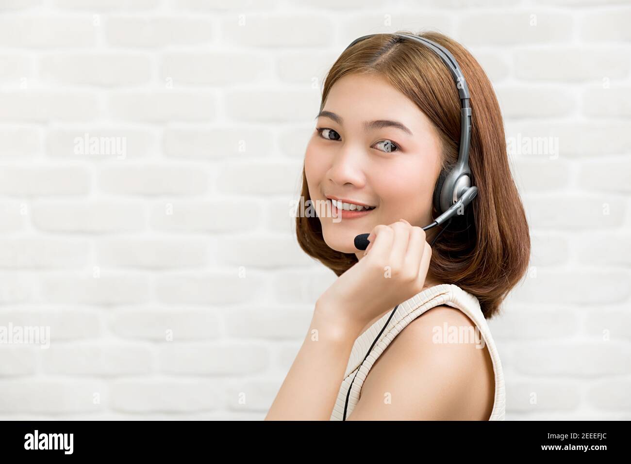 Casual Asian businesswoman wearing microphone headset  as a telemarketing customer service agent, call center job concept Stock Photo