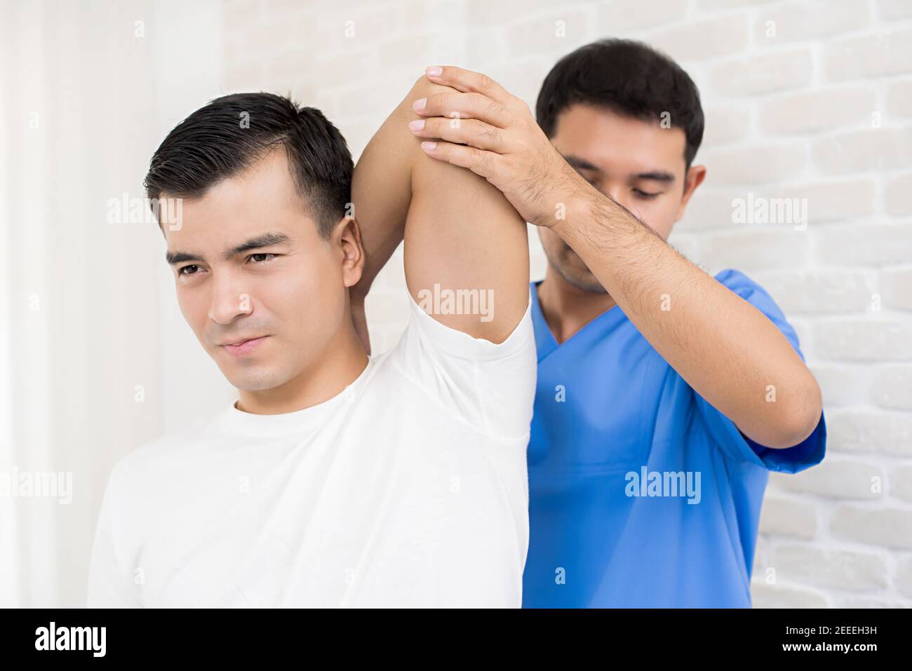 Therapist training rehab exercise, overhead tricep stretching, to male