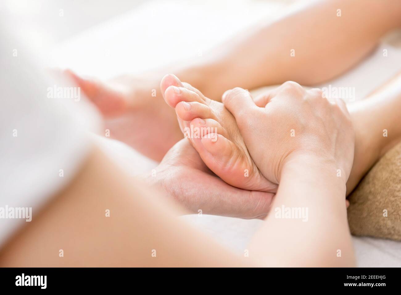 Professional therapist giving relaxing reflexology foot massage to a woman in spa Stock Photo