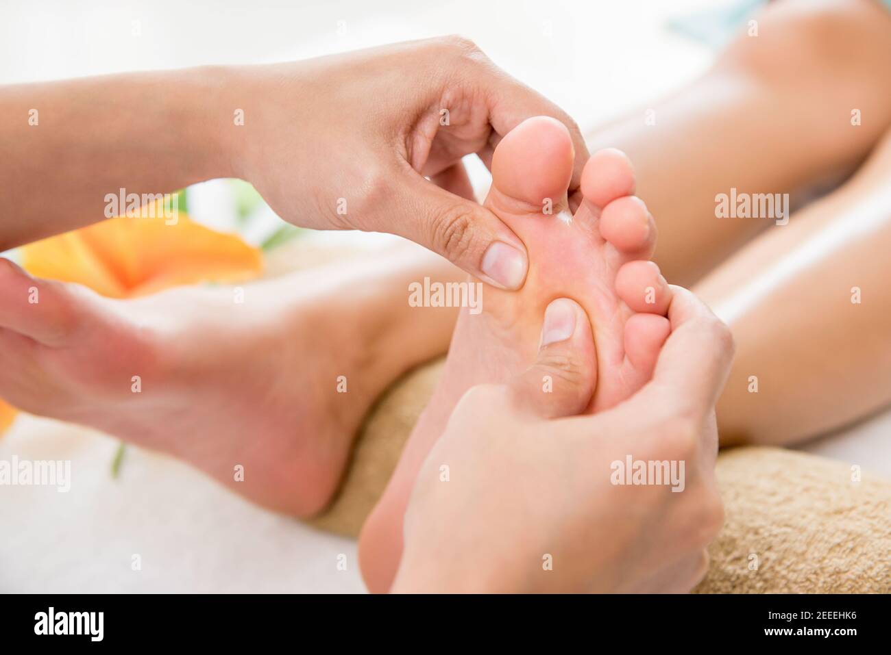 Professional therapist giving relaxing reflexology traditional Thai foot massage to a woman in spa Stock Photo